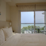 Image of bedroom with floor to ceiling window and bed in this condo in surfside, playa caracol