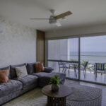 Image of living area with table, couch and window with view of the ocean and beach in this condo for sale in Solares, Sanctuary in Playa Caracol