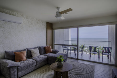 Image of living area with table, couch and window with view of the ocean and beach in this condo for sale in Solares, Sanctuary in Playa Caracol